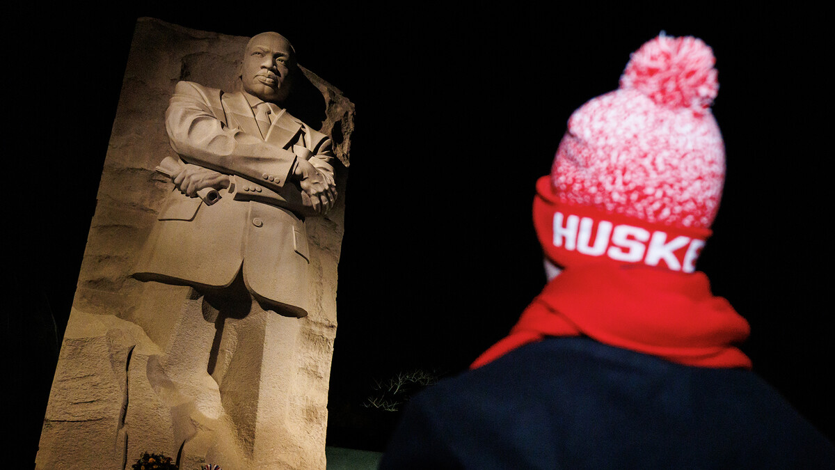 A student in a red and white stocking cap that says "Huskers" stands looking up to the Dr. Martin Luther King Jr. memorial in Washington, D.C.
