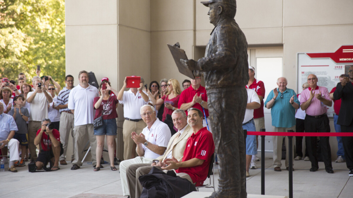 Mike Devaney, (Bob Devaney's son), Tom Osborne, the Cornhuskers' former head coach and athletic director, and Rob Devaney (Bob Devaney's grandson), look up at the just dedicated statue of Bob Devaney.  A commissioned statue of Hall-of-Fame football coach and former Cornhusker athletic director Bob Devaney was installed in the new East Memorial Stadium plaza Friday afternoon. 